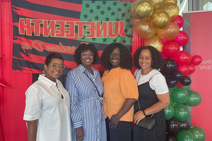 Attendees posed in front of Juneteenth flag and balloon display